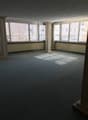 An empty room with carpeted floor, large windows, and two columns in the center.