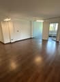 Empty room with wooden floors, white walls, and glass doors leading to another room.