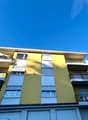 4 story building, yellow and white exterior, multiple balconies, garage