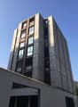 High-rise building, grey stone walls, multiple windows, ground floor with garage entrances