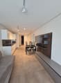 Modern kitchen with a dining area, living room with a couch, and a minimalist interior design