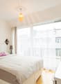 white bed, white bedhead, white pillow, brown blanket, lamp, tv, wooden floor