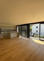 Modern kitchen with countertops, wooden floors, glass sliding doors leading to balcony