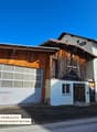 2-story building, white and wooden exterior, large garage, multiple windows, street-facing entrance