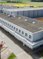 2 story building, metal facade, concrete parking lot, large windows, cars parked