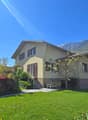 2 story house, yellow exterior, brown shutters, mountain view, garden, bench