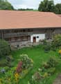 traditional wooden house, tiled roof, front garden with lawn and plants, wooden door