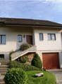 2 story house, white stucco, brown windows, brown door, stone driveway, stairs leading to wooden front door, garage