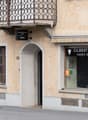 2-storey building with an arched entrance, brown wooden balcony, white awning, Gilbert Vincent shop at ground floor, and several windows