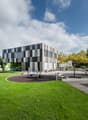 Contemporary architectural building, checkerboard pattern facade, children's playground, trees, bench, table tennis