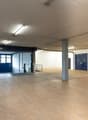 large open space, concrete floor, metal beams, large blue doors, storage boxes, stacks of wooden pallets