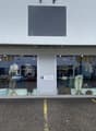 Storefront with glass windows and parking area in front, mannequins and displayed clothes inside