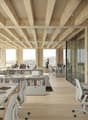 modern office with wooden beams, large windows, desks, chairs, bookshelves, laptops, monitors, and a view of the mountains