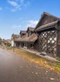 Detached house, brown wooden walls, grey roof, arched window