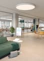 Open floor plan with breakout areas, seating areas, large windows, and office equipment.