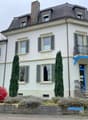 white building, 3 stories, multiple windows, balcony on second floor, entrance stairs