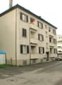 4 story building, balconies, parking lot, small shed