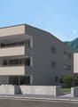3-story modern apartment building with beige exterior, balconies, and surrounded by trees and mountains in the background.