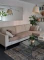 Living room with a beige sofa, glass coffee table, carpet, and a large mirror on the wall.