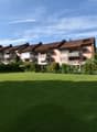 Apartment building with brown roofs, several floors, balconies, located in a green area with a large lawn