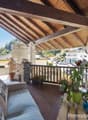 wooden deck with railings, stone wall, potted plants, outdoor furniture, view of the surroundings