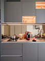 Modern kitchen with gray cabinets, wooden countertop, built-in Siemens microwave oven, various kitchen appliances and utensils, open shelving with decorative items