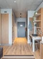 Open-plan studio apartment with concrete ceiling, wooden floors, built-in storage, desk area, sofa, and a balcony or terrace visible.