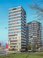 Two high-rise buildings, brown and white facades, many windows, curved architecture on the right building.