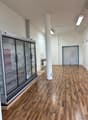 Large open space with hardwood floors, glass display refrigerators, and a door leading to another room.