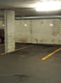 underground parking lot, concrete walls, yellow parking lines, parked red car, drain cover, pipe on wall