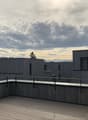 Rooftop terrace with wooden flooring, metal railings, and a view of the surrounding area