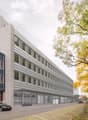 Office building with 3 floors, glass windows, Tesla branding, paved road, trees, and parked cars