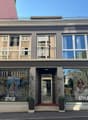 3-story building with 2nd floor balcony, 2 entrance, 3 windows, plants, street view
