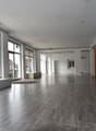 Large open space, hardwood floors, large windows, bench, and industrial-style interior design.