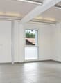 Empty room with sliding doors, windows, tiled floor, and overhead lighting.