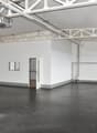 Empty room with white walls, black floor, windows, and an open door.