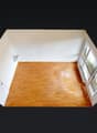 Empty room with wooden floor, white walls, and windows.
