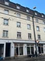 multistory building, large windows, ground floor commercial space, several people walking