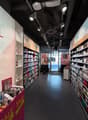 Cosmetics store with shelves full of products, sale signs, and a large wall with the word 'ERFUL'.