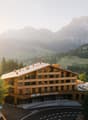 wooden hotel, mountainous surroundings, outdoor seating area, large windows, curved roof, multiple floors