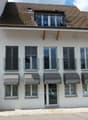 white building, brown roof, multiple windows, balconies, awnings, entrance door