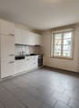 White cabinets, grey tiled floor, sink, faucet, oven, dishwasher, dishwasher, window with view