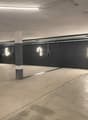 Large open parking garage with concrete floor, concrete columns, and overhead lighting
