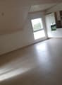 empty room with tiled floor, white walls, kitchen area with window, built-in appliances