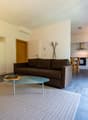 modern living area with a couch, glass coffee table, rug, modern kitchen with dining table, and microwave
