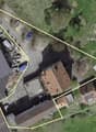 Aerial view of a property with several buildings, including a large building with a gray roof, a smaller building with a brown roof, and a building with a red roof. The property is surrounded by a yellow line indicating the boundaries.