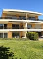 2 story house, yellow exterior, multiple balconies, large windows, surrounded by greenery