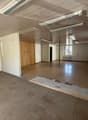 Empty room with tiled floor, white walls, wooden ceiling, and multiple windows.