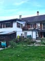 White house, brown roof, balcony, large front yard, attached wooden garage, chimney
