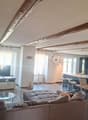 Living room with wooden floor, large sofa, dining table, TV, kitchen area, wooden beams on ceiling